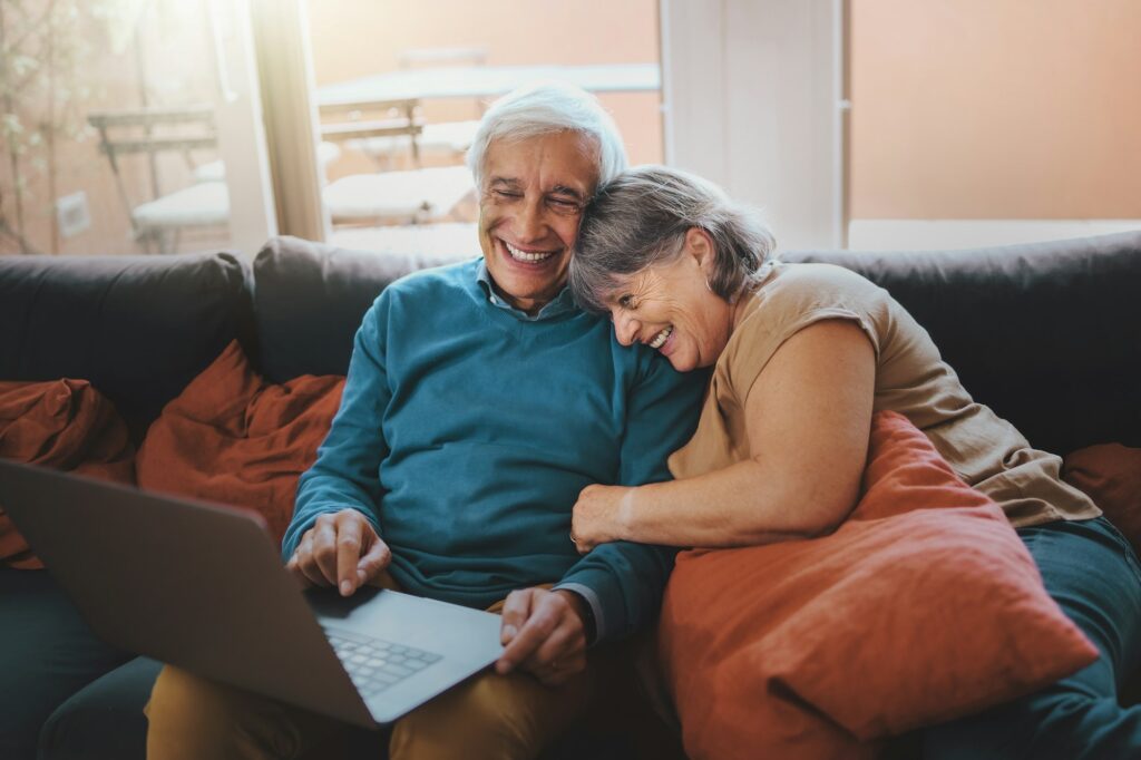 Retired couple watching funny video content on a laptop screen