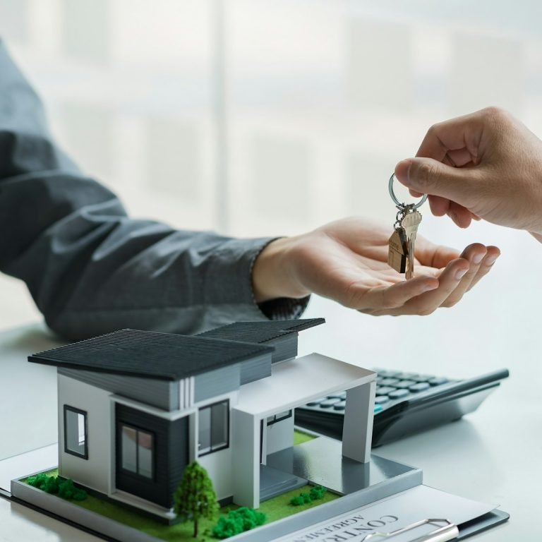 Real estate agent hand over the house key to customers after signing a real estate sales contract